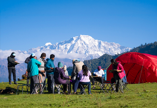 Group of trekkers sitting around a camping table inside a white tent