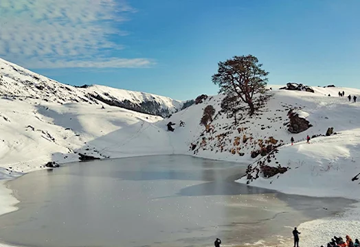 Group of trekkers sitting around a camping table inside a white tent