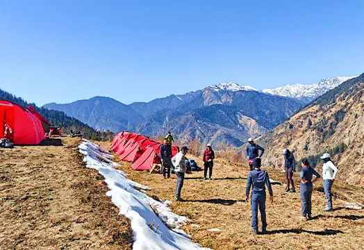 Group of trekkers sitting around a camping table inside a white tent