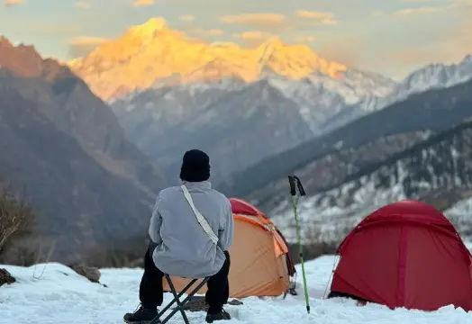 Group of trekkers sitting around a camping table inside a white tent