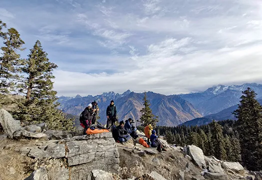 Group of trekkers sitting around a camping table inside a white tent