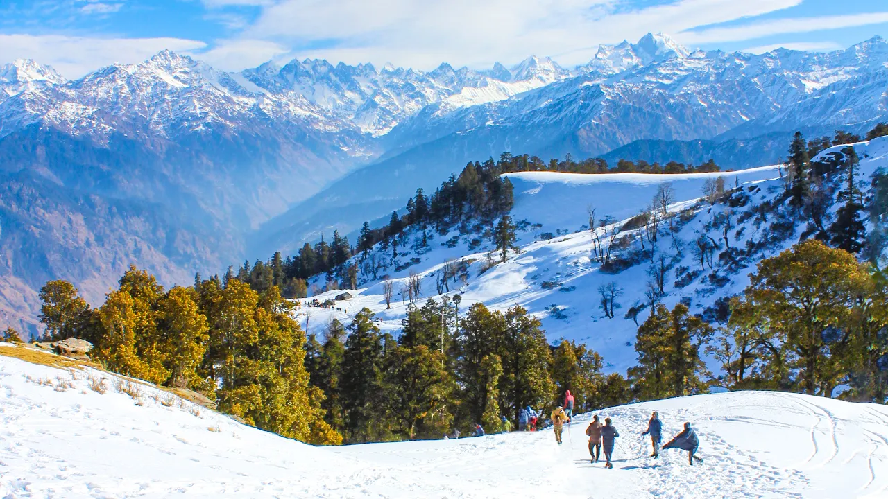 Trekkers walking through a peaceful meadow on the Kedarkantha trek