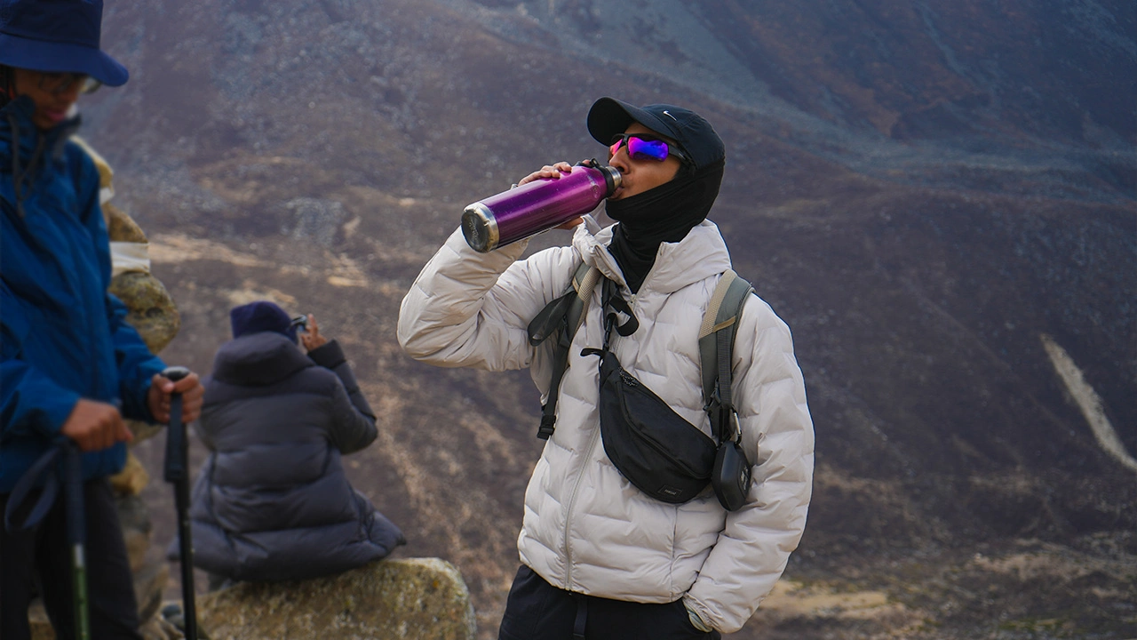 Trekker staying hydrated during high-altitude Himalayan trek, Trek The Himalayas