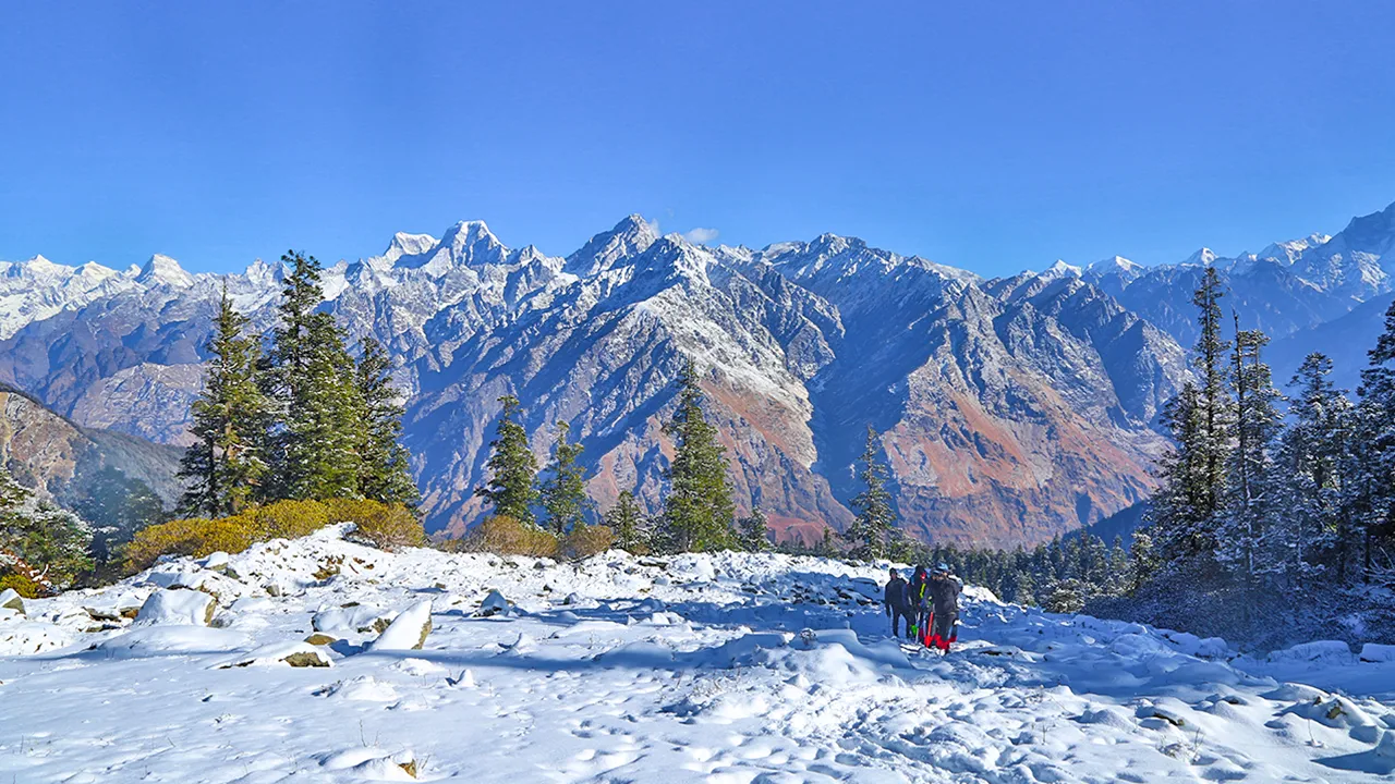 Winter view of Kuari Pass with trekkers on the snowy path