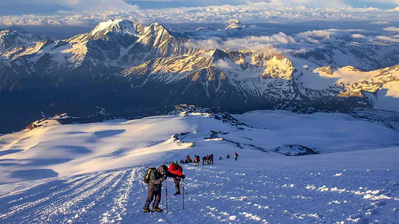 Trekkers ascending snowy mountain slopes during sunrise on a scenic European hike, Trek The Himalayas