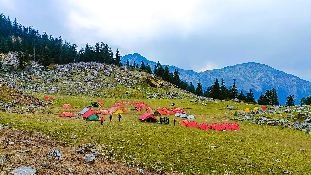 Trekkers enjoying on the campsite of Trek the Himalayas on a wide green meadow during the Kuari Pass trek campsite
